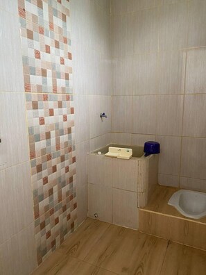 Une petite salle de bain avec un plancher en bois, un mur carrelé à motifs à carreaux, des toilettes et un lavabo bleu.