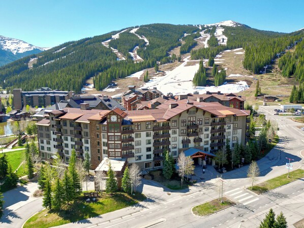 A multi-story hotel with a central courtyard, surrounded by a ski resort area with visible ski trails and mountains in the background. - Wonderful Condo Right in Center Village! 3 Outdoor Hot Tubs PP321 (Copper Mountain)