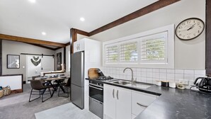 Una cocina moderna con refrigerador empotrado, estufa y pileta. Hay una zona de comedor con una mesa y sillas.