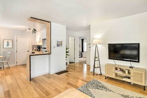 Un soggiorno moderno con parquet, una televisione, un mobile in legno e un'area pranzo con una sedia e un tavolo.