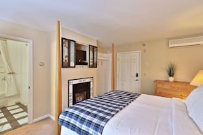 A bedroom with a bed, a fireplace, a television mounted above it, a door, and a dresser. - The Birch Ridge: Blue Velvet Room #10 - Queen Suite in Killington, Vermont. Hot Tub. Lounge. (Killington)
