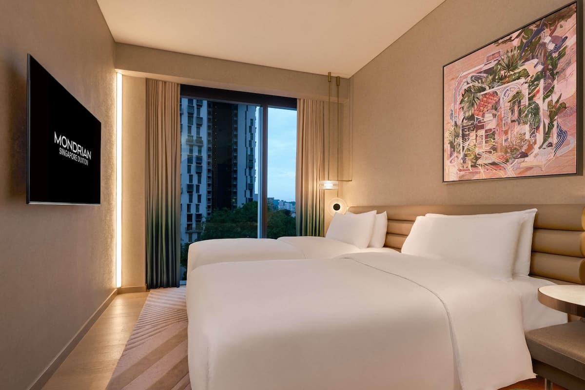 Een hotelkamer met een groot bed, een bureau en een televisie waarop 'MONDRIAN SINGAPORE DUXTON' staat.