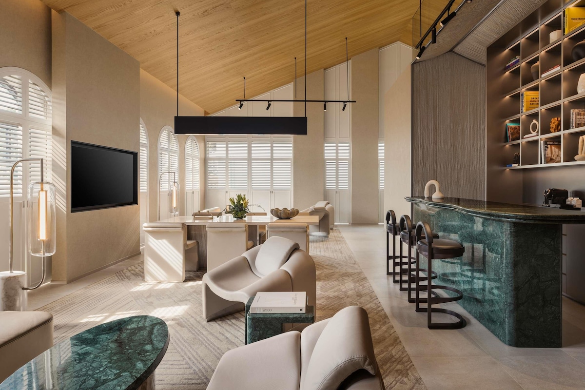 Una sala de estar moderna con techo de madera, televisor de pantalla plana, comedor y cocina con una isla de mármol.