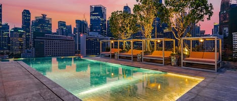 Piscina en la azotea con asientos de descanso y vista al horizonte de la ciudad.