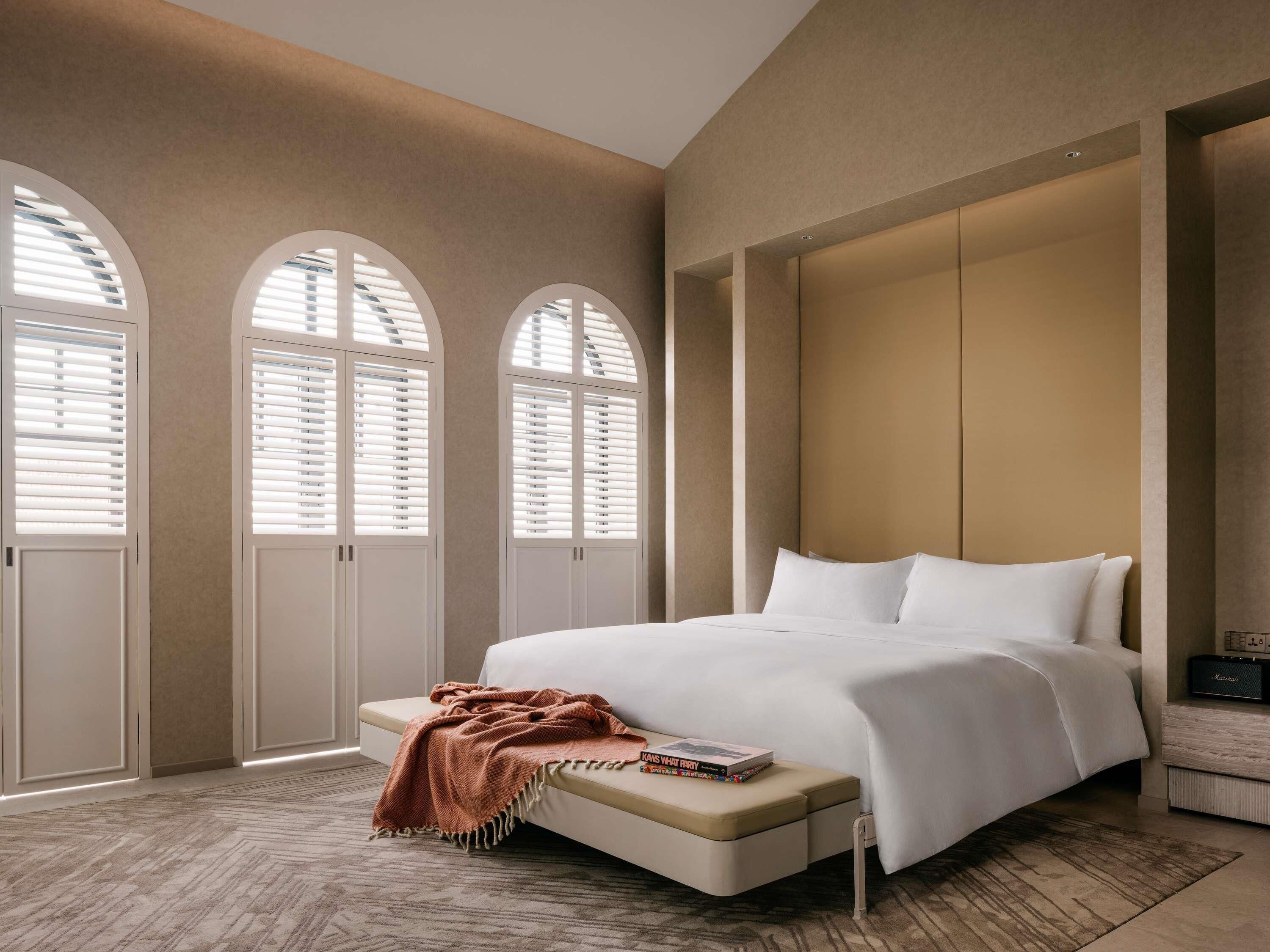 Ein Schlafzimmer mit einem großen Bett, gewölbten Fenstern und einem eingebauten Kleiderschrank.