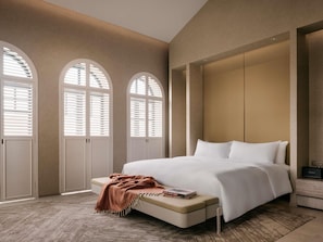 Un dormitorio con una cama grande, ventanas arqueadas y un armario empotrado.