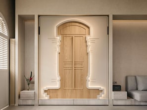 Interior moderno com porta de madeira com design único, uma mesinha com um vaso e um sofá cinzento.