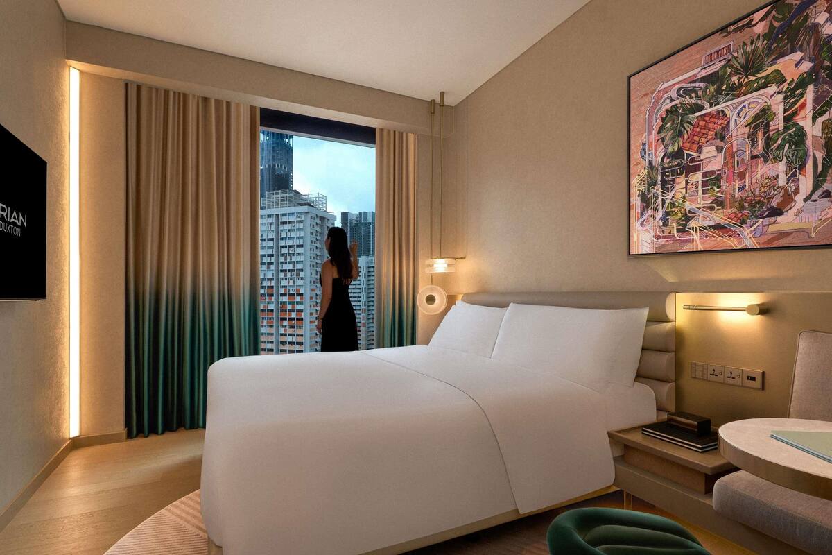 Een hotelkamer met een groot bed, een bureau, een stoel, een schilderij en uitzicht op hoge gebouwen.