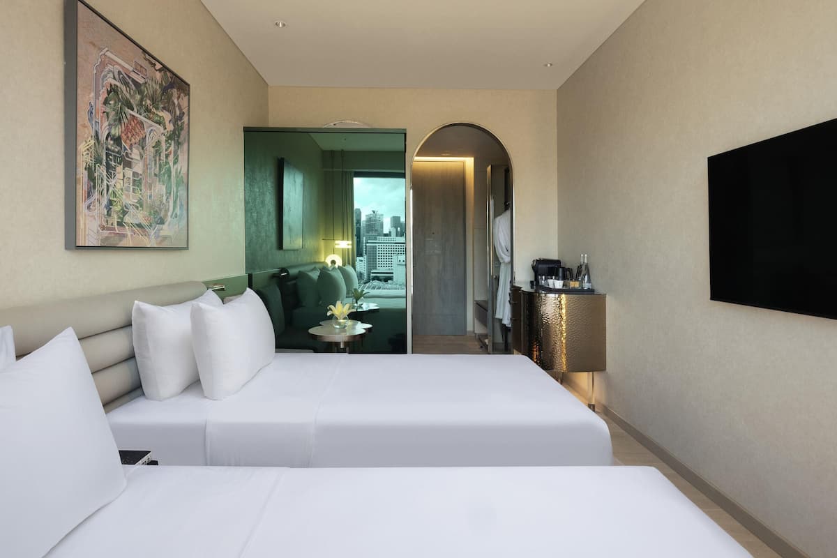 Een hotelkamer met twee bedden, een schilderij, een koffieapparaat en uitzicht op de stad.