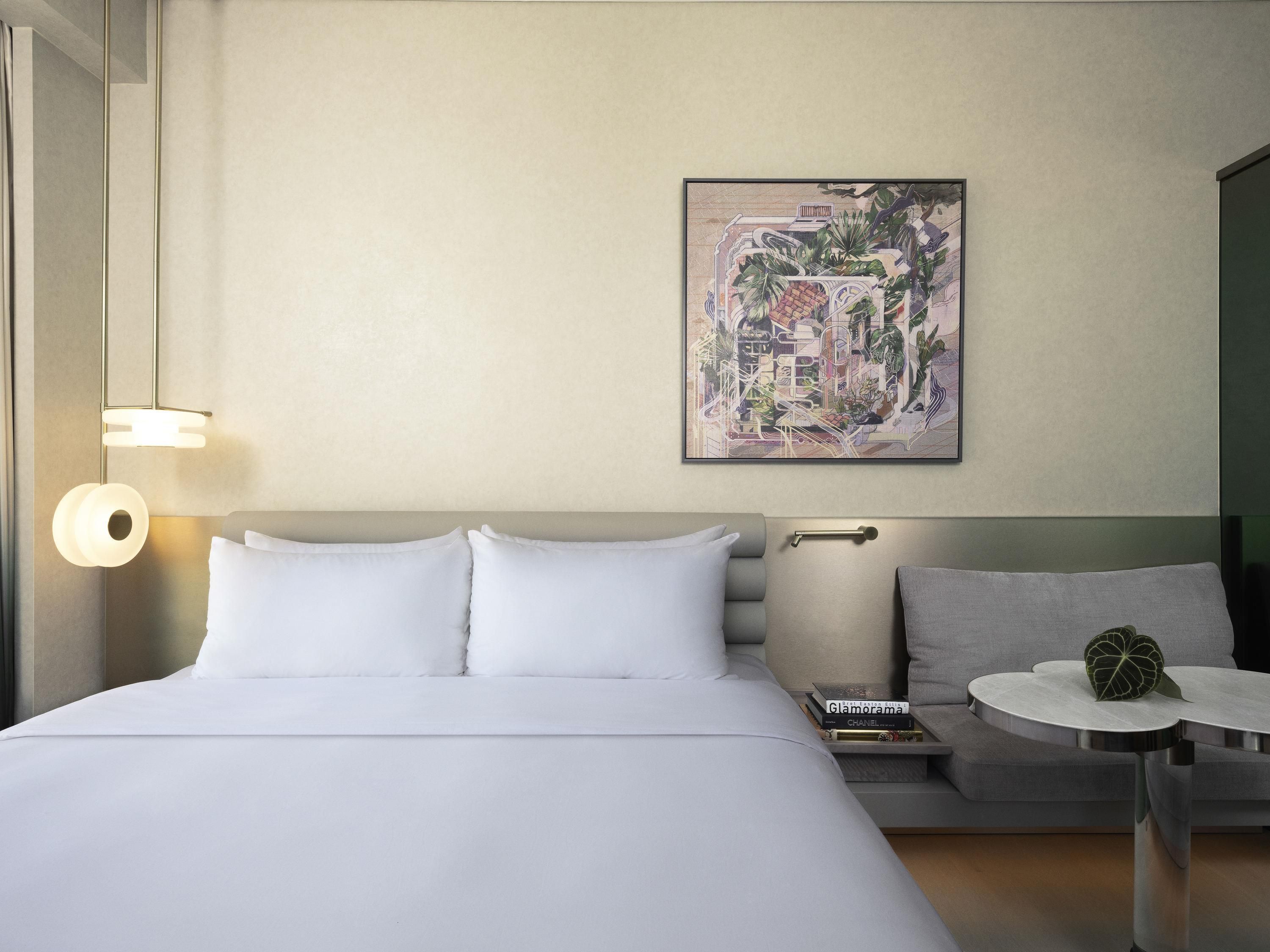 Een hotelkamer met een groot bed, een klein rond tafeltje, een bank en een kunstwerk aan de muur.