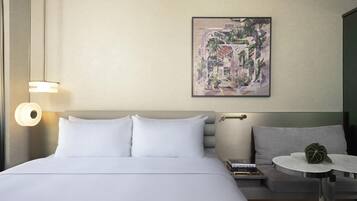 Een hotelkamer met een groot bed, een klein rond tafeltje, een bank en een kunstwerk aan de muur.