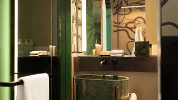 Un baño moderno con ducha de vidrio, lavamanos de mármol y perchero para toallas.