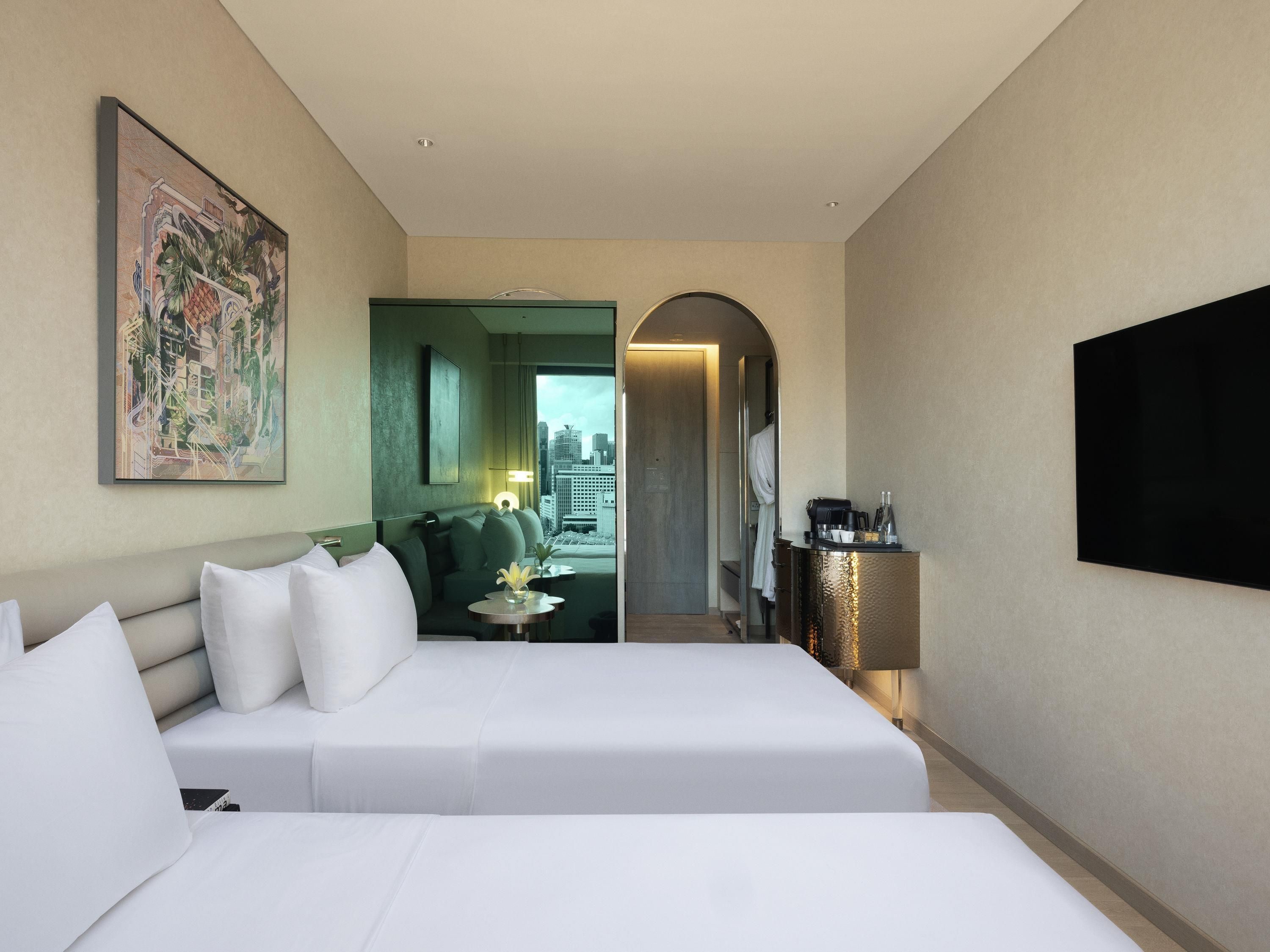 Ein Hotelzimmer mit zwei Betten, einem Gemälde, einer Kaffeemaschine und Blick auf die Stadt.