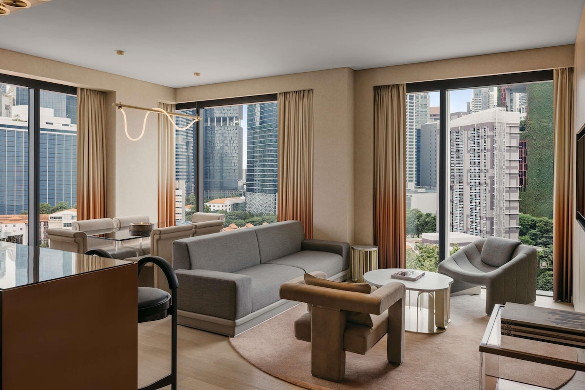 Un salón moderno con sofá, sillón, mesa de centro y un separador de vidrio.
