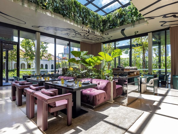 A modern interior with a high ceiling, green plants, and a view of the outside. - Mondrian Singapore Duxton (Singapore)