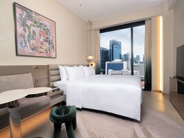 Una habitación de hotel moderna con una cama, un escritorio y vistas del horizonte urbano.