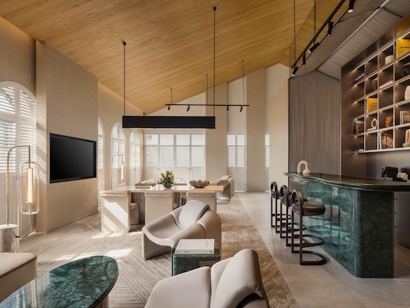 Una sala de estar moderna con techo de madera, televisor de pantalla plana, comedor y cocina con una isla de mármol.