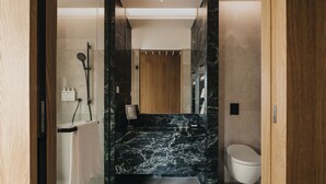 A modern bathroom with a marble vanity, a glass shower enclosure, and a wooden door. - Mondrian Singapore Duxton (Singapore)