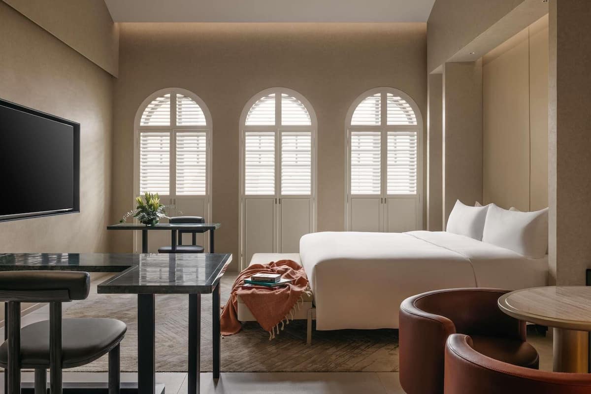 Een moderne hotelkamer met een bed, een bureau, een stoel, een televisie en gebogen ramen.