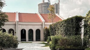 A modern building with a reflective water feature in front, arched doorways, and a red roof. - Mondrian Singapore Duxton (Singapore)