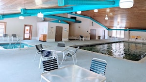 An indoor swimming pool area with a wooden ceiling, blue structural beams, and a clock on the wall. - Secluded Chalet in Michaywe w/ pool access. Golf + Ski/Snowmobile paradise. (Gaylord)