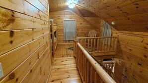 Interior de madera con una escalera que lleva a una puerta.