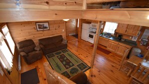 A cabin interior with a living area featuring a sofa, a rug, and a dining table. - Eagle's Nest - Sleeps up to 10 (Moravia)