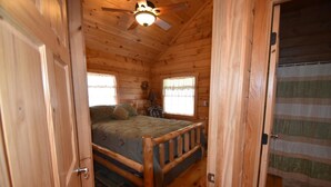 A wooden cabin bedroom with a bed, a ceiling fan, and two windows. - Eagle's Nest - Sleeps up to 10 (Moravia)