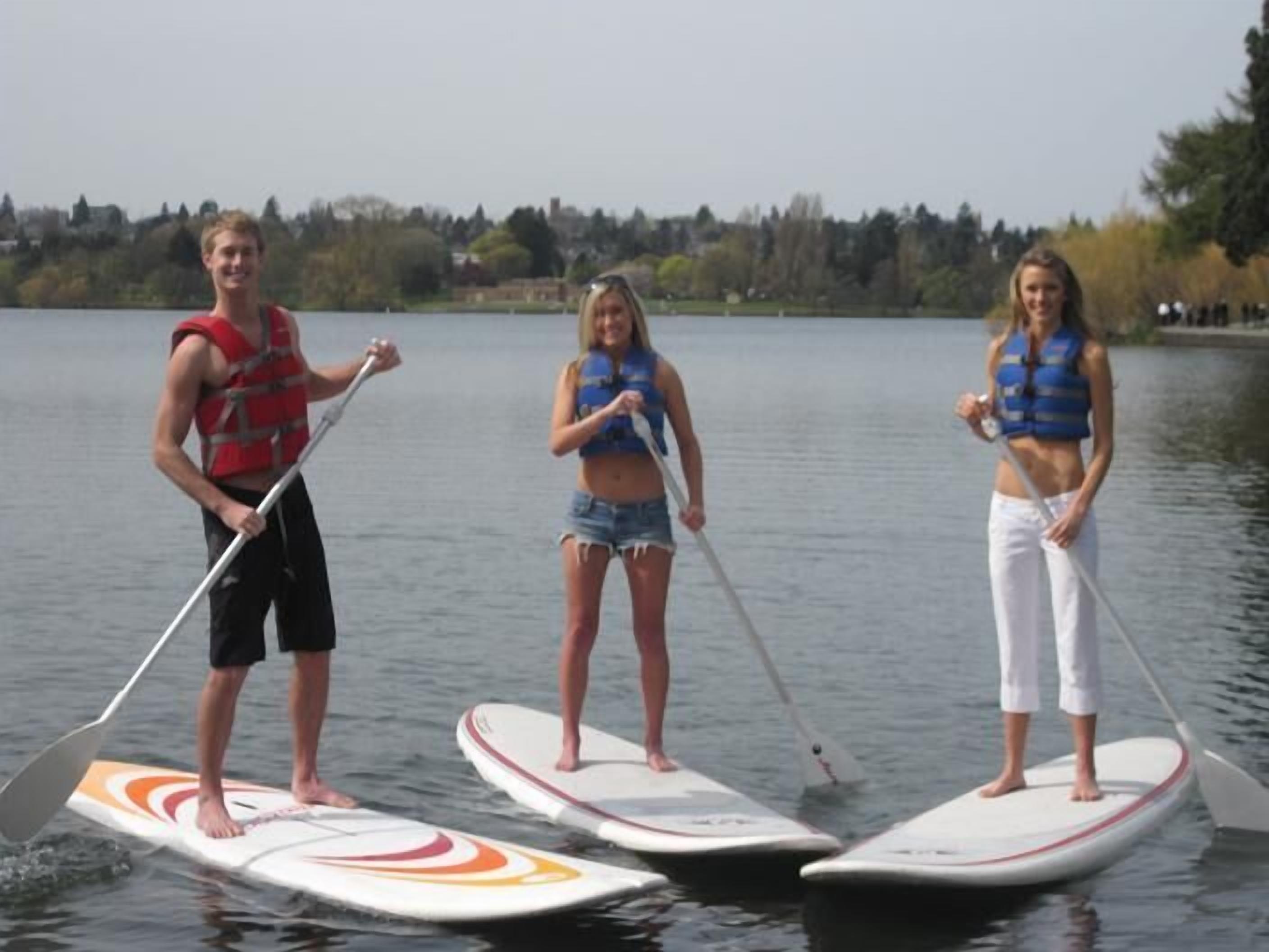 Three people stand on paddleboards in a calm lake.