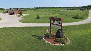 A sign for Foxtail Cabins with a flag, surrounded by a well-maintained lawn and a gravel path leading to a building. - Full Campus Rental - Weddings/Family Reunions (Moravia)