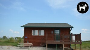 A wooden cabin with a deck, a picnic table, and a mailbox.