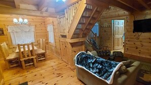 A wooden cabin interior with a dining area, a sofa, a television, and a staircase. - Elk - Sleeps up to 6 (Moravia)