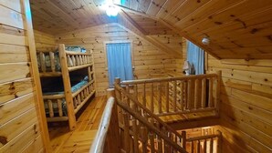 A wooden cabin interior with a bunk bed, a small window with curtains, and a wooden staircase. - Elk - Sleeps up to 6 (Moravia)