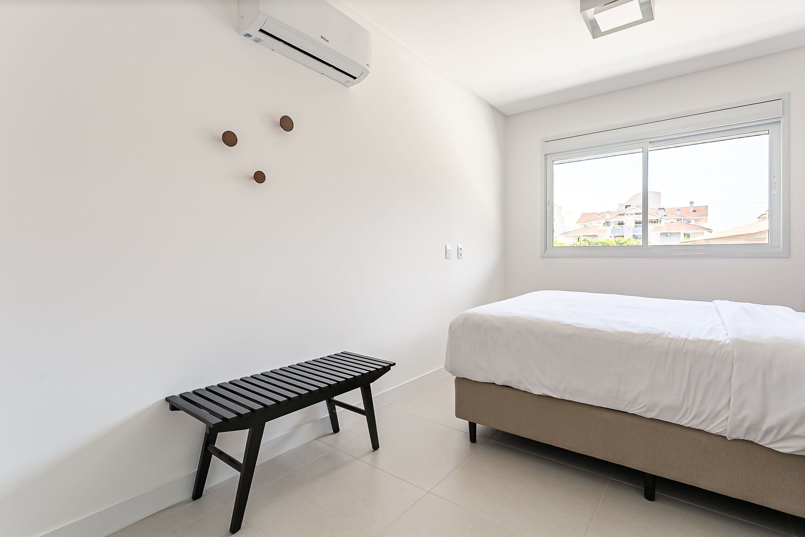A bedroom with a bed, a bench, and an air conditioning unit.