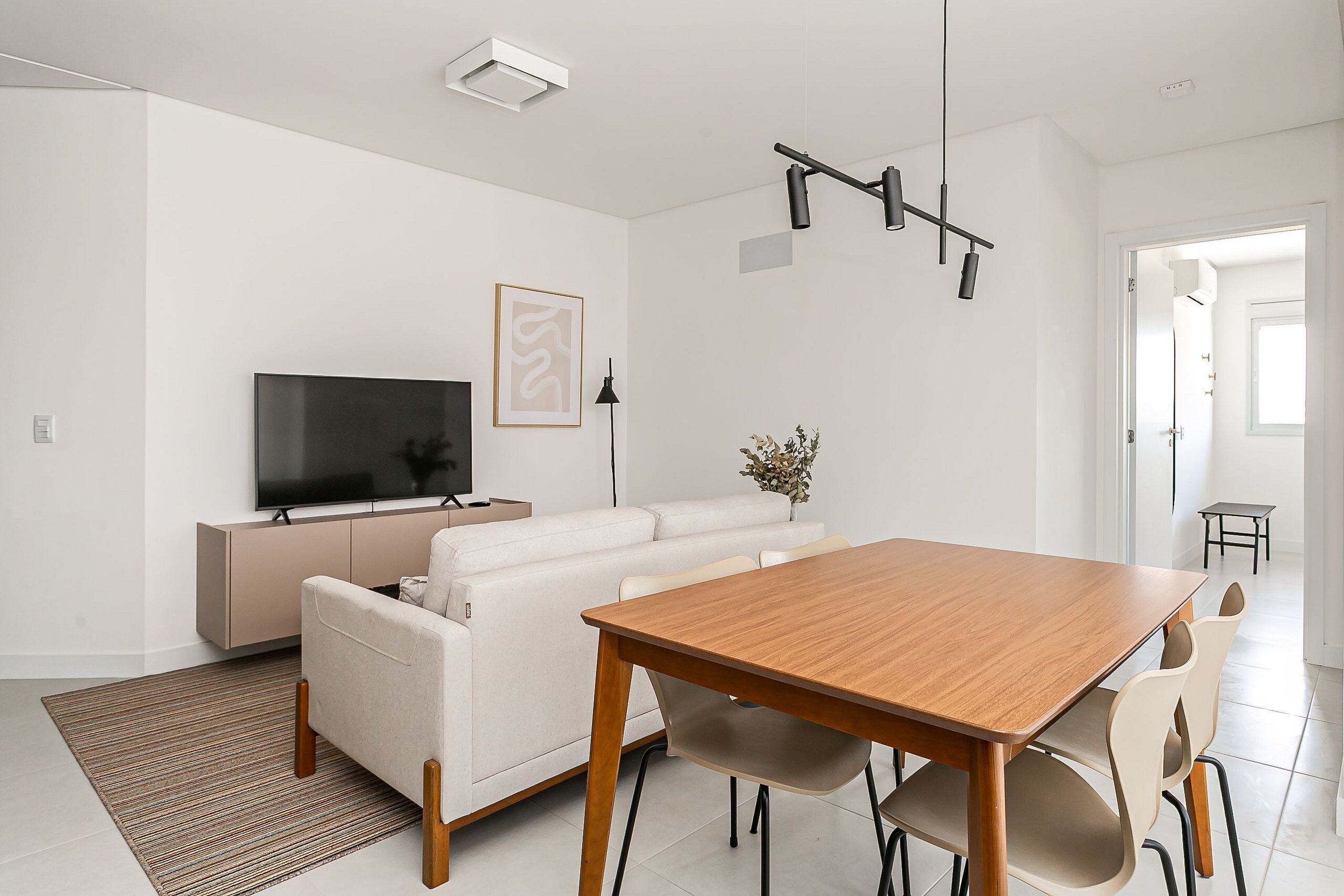Ein modernes Wohnzimmer mit Sofa, Fernseher und Esstisch.