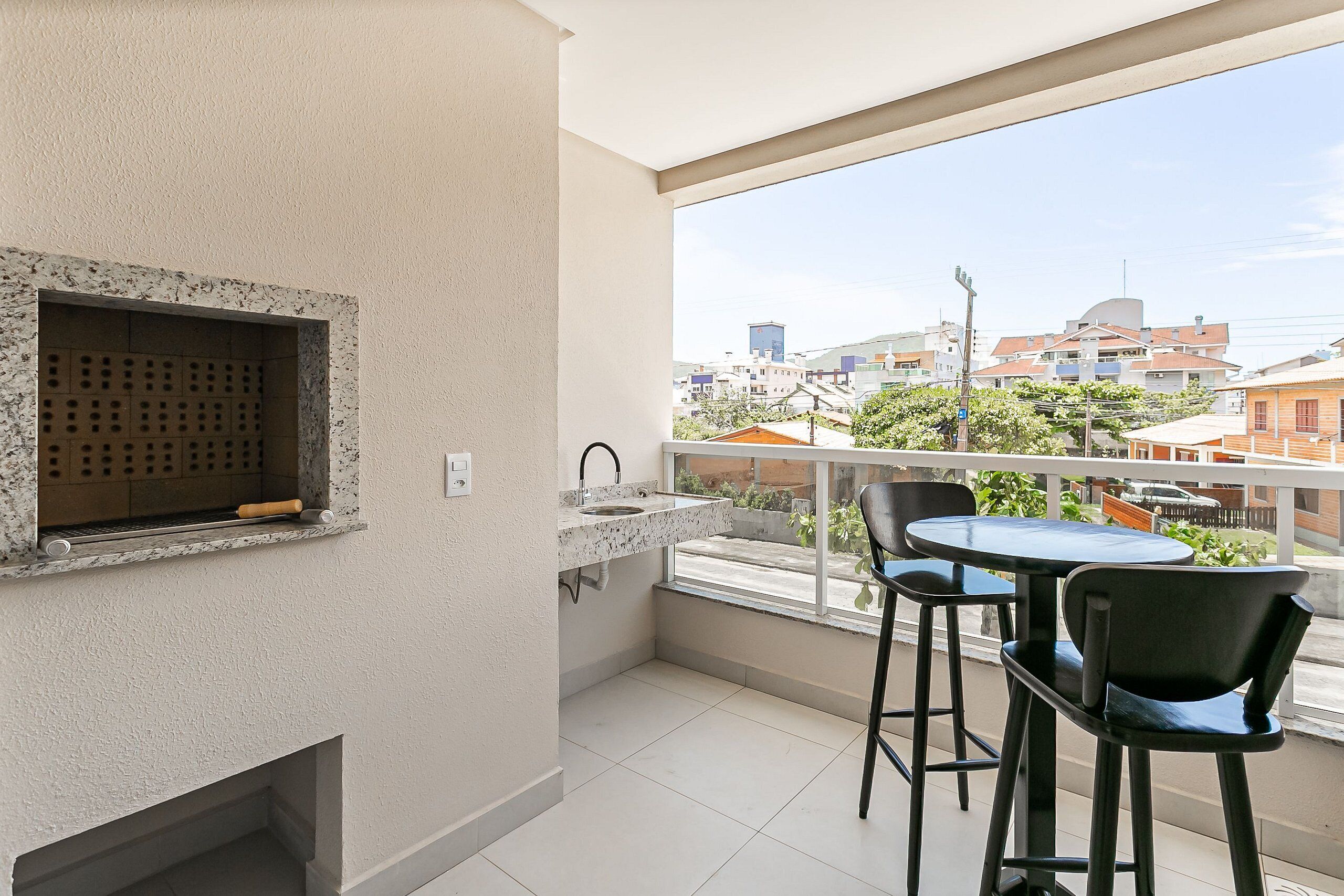 Un balcon doté d’un coin cuisine, comprenant un évier et un barbecue, ainsi que de deux chaises.