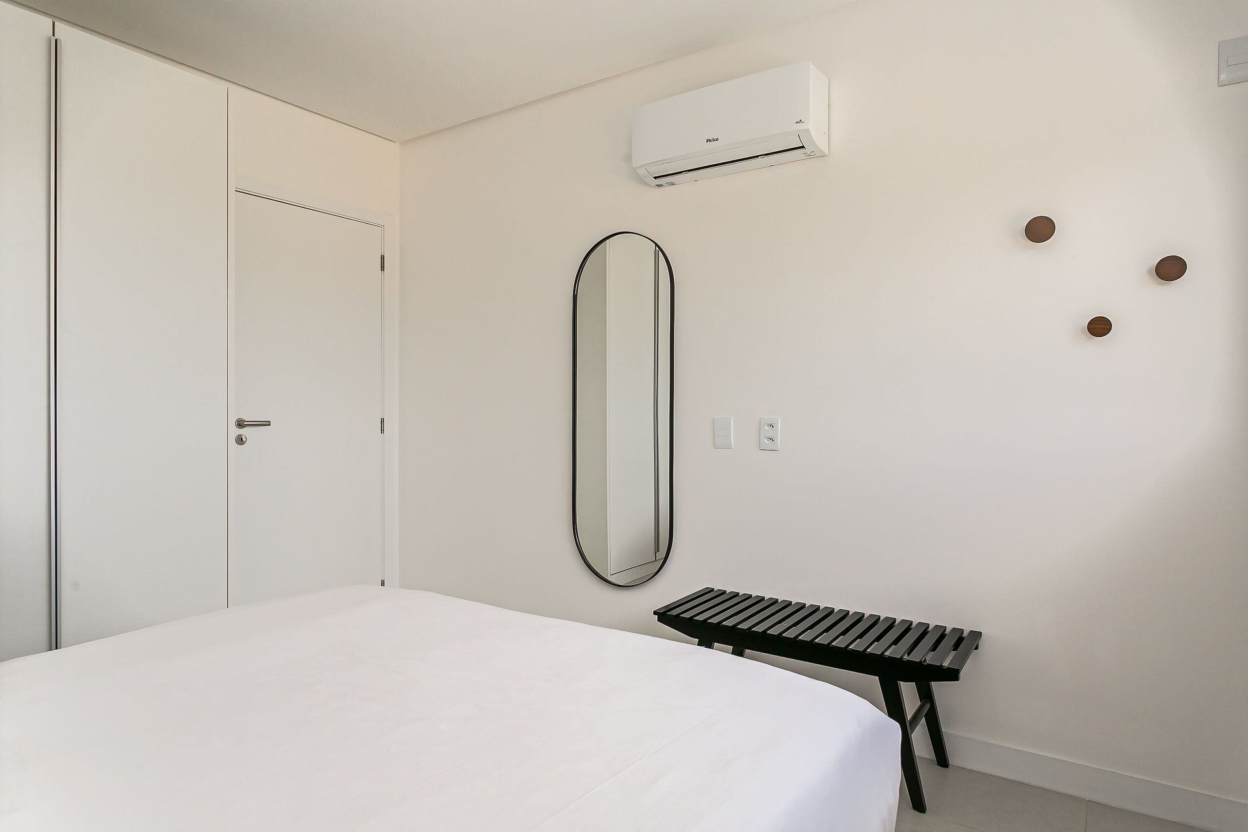 Un dormitorio con cama, mesita de noche, espejo, armario y aire acondicionado.