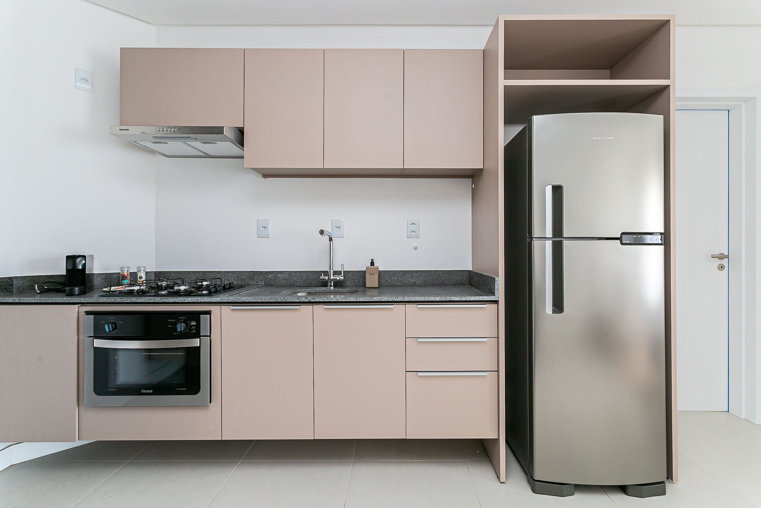 Eine moderne Küche mit Edelstahlgeräten, darunter ein Kühlschrank und ein Backofen, sowie hellem Korpus.