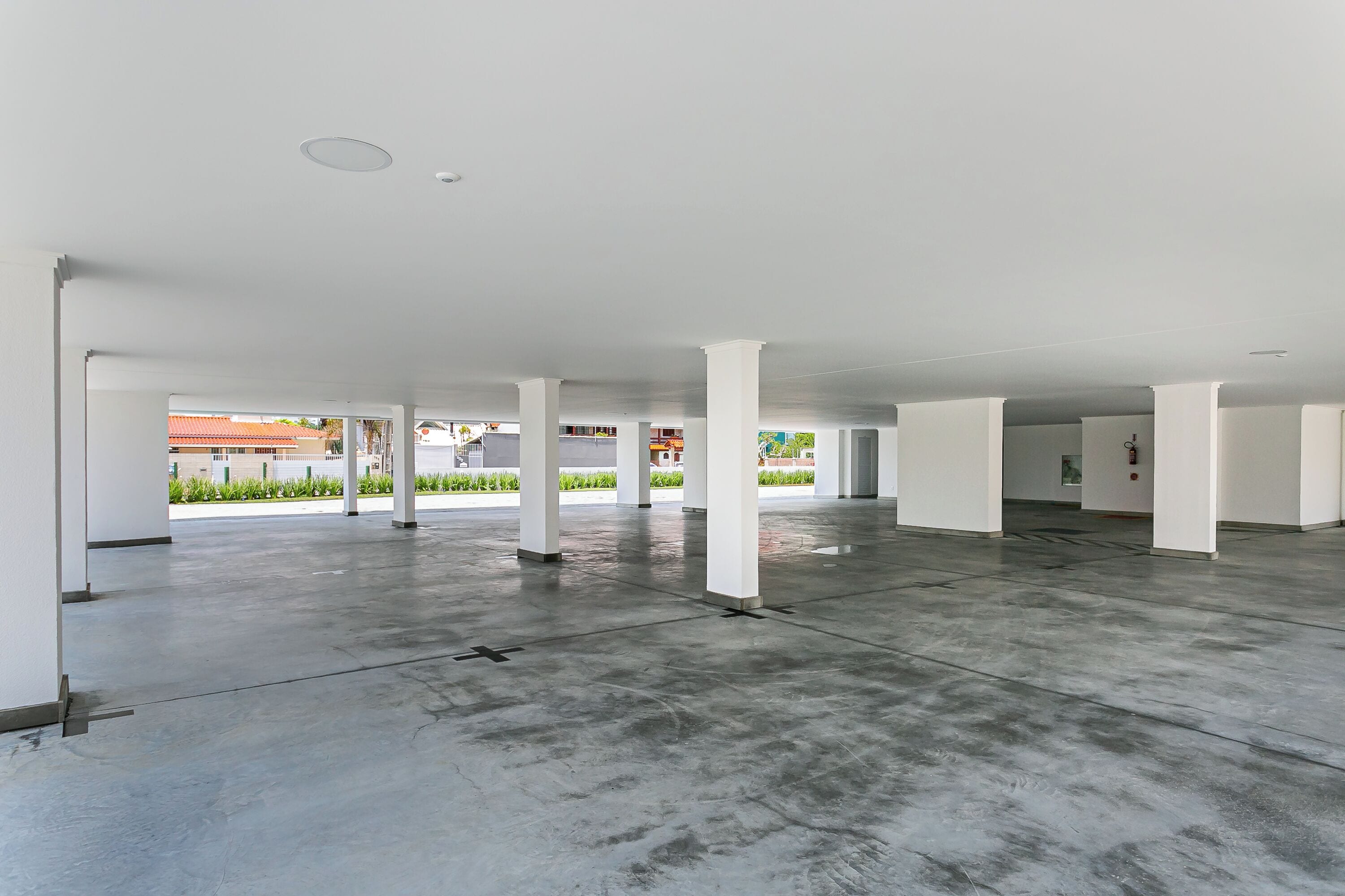 An interior with a high ceiling, white pillars, and a concrete floor.