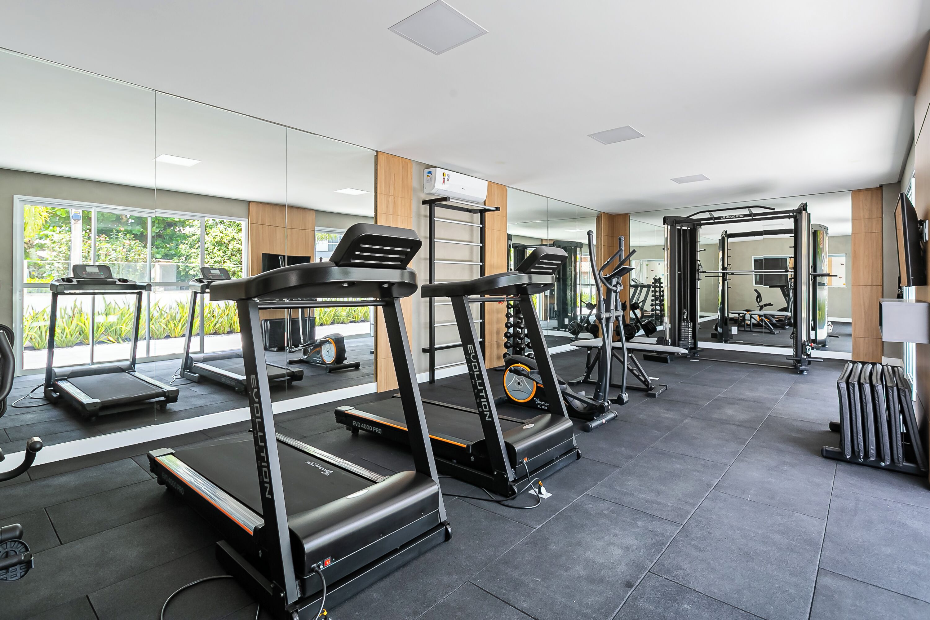 A gym with treadmills, weight machines, and a mirrored wall.
