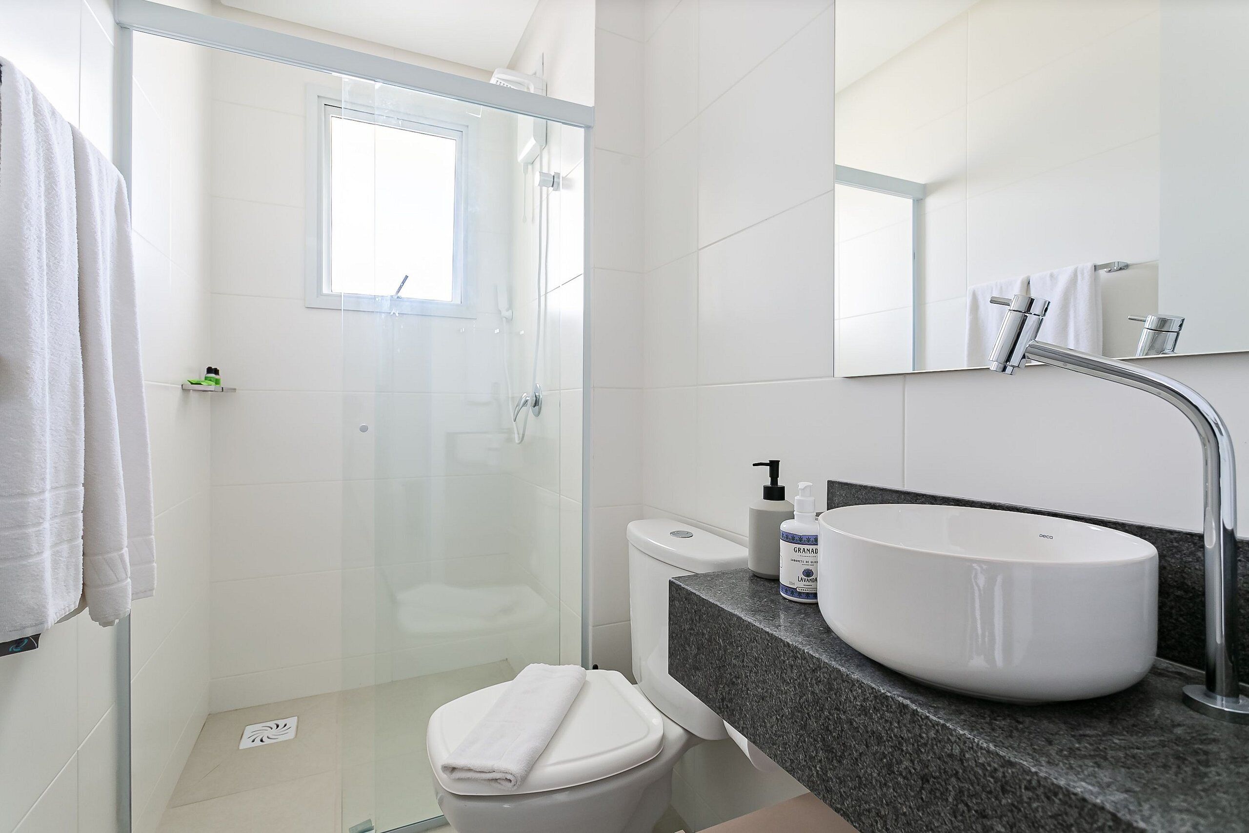 A modern bathroom with a glass shower enclosure, a white sink, and a toilet.