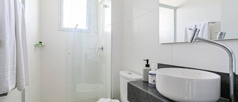 A modern bathroom with a glass shower enclosure, a white sink, and a toilet.