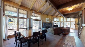 A spacious living area with a wooden ceiling, large windows, a fireplace, and a dining table with chairs. - Spacious Cabin Vibe w/ lots of Wood - Easy walk/ride to Village, Lodge and River (Sunriver)