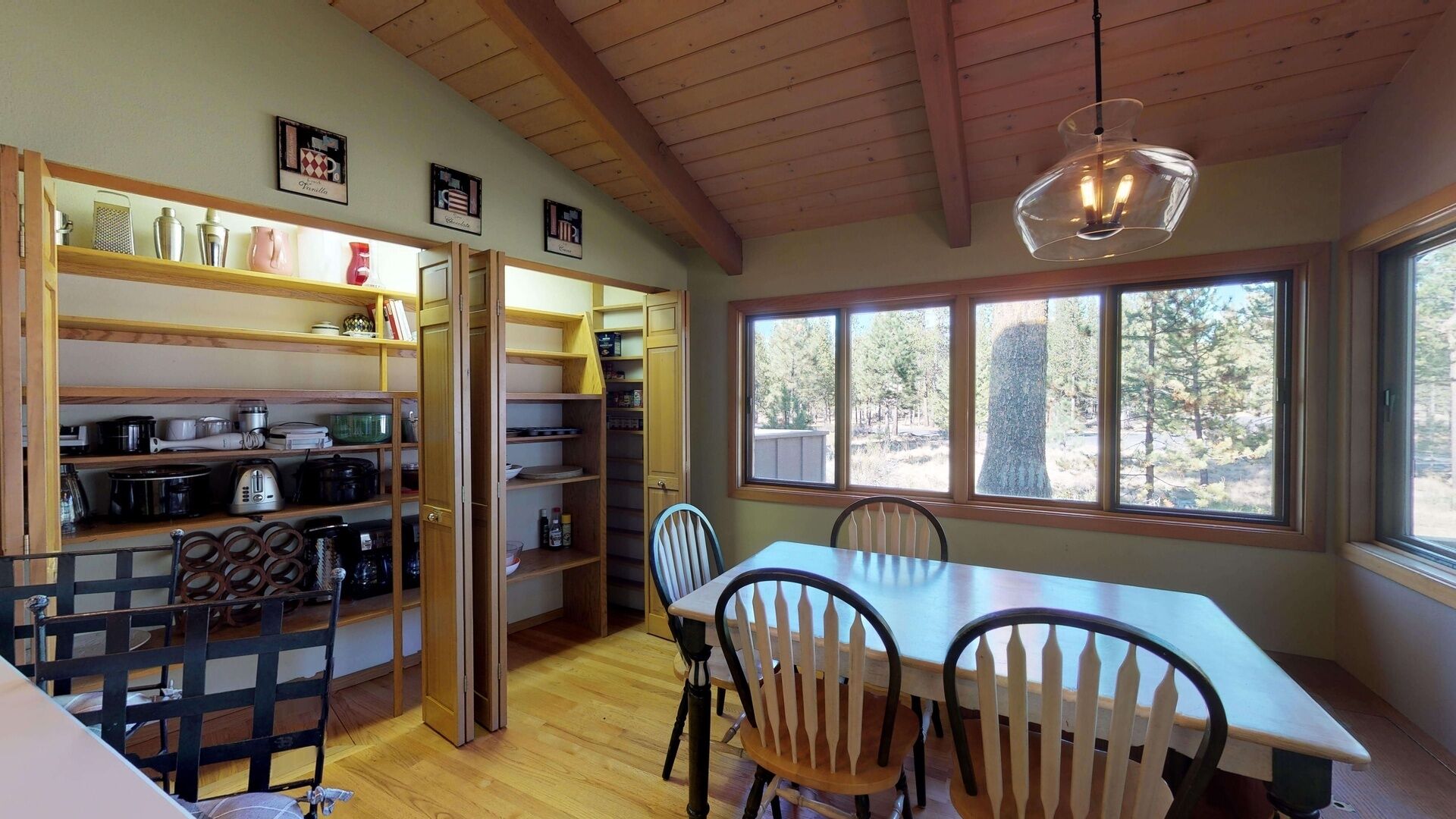 A kitchen with wooden shelves, a dining table, and chairs.