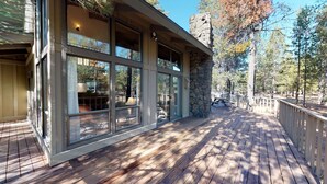 A wooden deck with large windows overlooking a forested area. - Spacious Cabin Vibe w/ lots of Wood - Easy walk/ride to Village, Lodge and River (Sunriver)