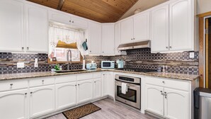 A kitchen with white cabinets, a granite countertop, a stainless steel oven, and a microwave. -  AC, Walk 2 Lake, Go Karts, Dining & Shops, King Bed, 55" TVs+Fenced Yard 4 Pet! (Big Bear)