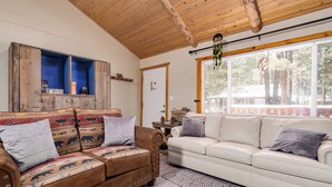 A living room with a brown sofa and a white sofa, a wooden ceiling, and a window with blinds. -  AC, Walk 2 Lake, Go Karts, Dining & Shops, King Bed, 55" TVs+Fenced Yard 4 Pet! (Big Bear)