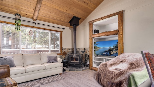 A cozy living room with a sofa, a fireplace, and a large window. -  AC, Walk 2 Lake, Go Karts, Dining & Shops, King Bed, 55" TVs+Fenced Yard 4 Pet! (Big Bear)