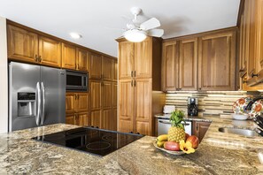 Una cocina con armarios de madera, electrodomésticos de acero inoxidable, encimera de granito y un frutero.