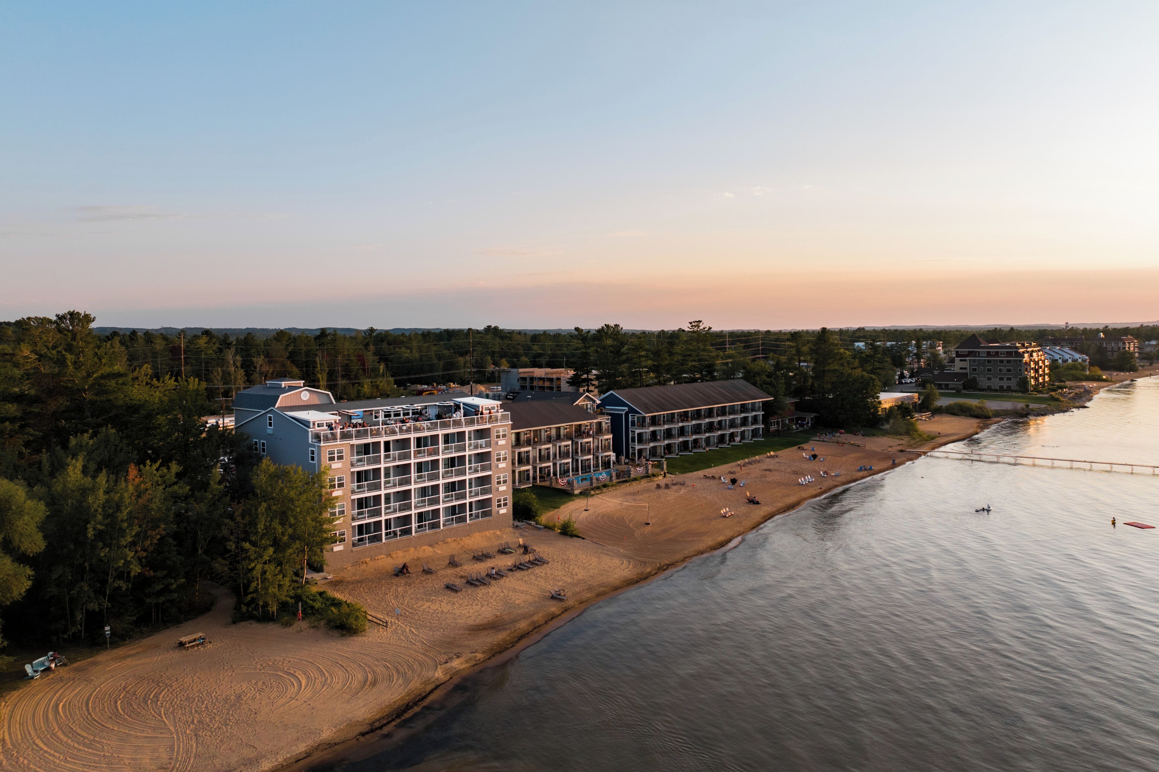 A coastal hotel with multiple buildings, a beach, and a river.